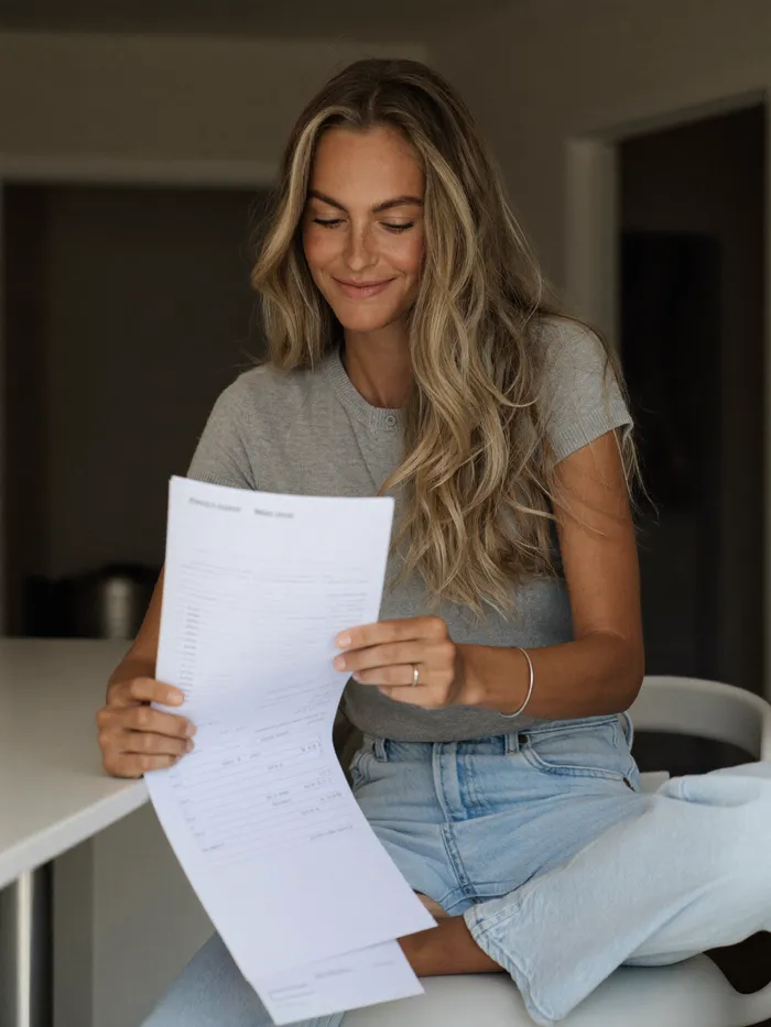 A woman reviewing a medical bill at her kitchen table, reassured